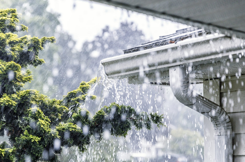 rainfall landing on a roof with water coming off the gutters