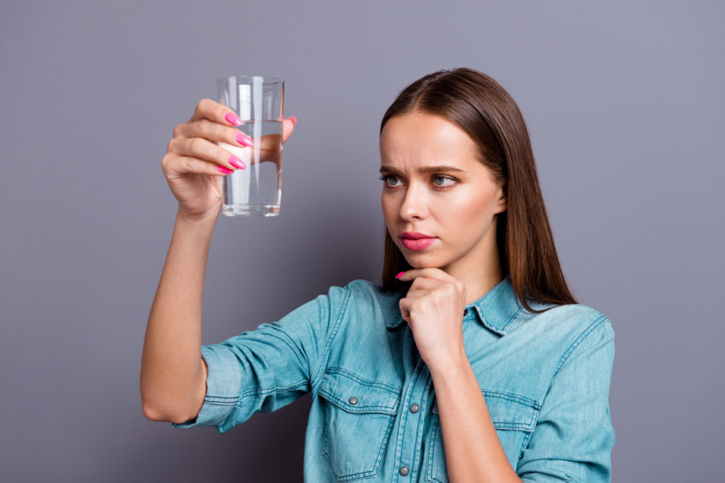 Close up portrait of not sure in water quality woman wearing casual jeans shirt outfit clothes isolated on grey background