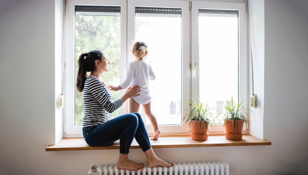 woman with her daughter in front of windows