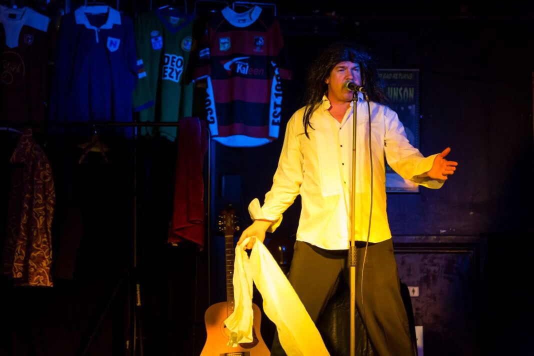 man in wig on stage singing into a microphone