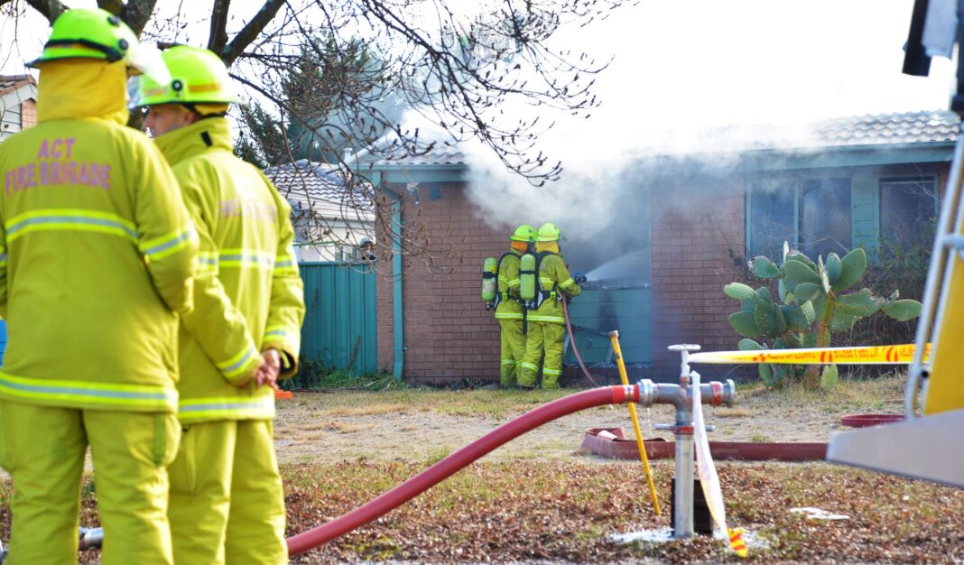 Four trainee fire fighters using fire hoses to extinguish a house fire during a training exercise