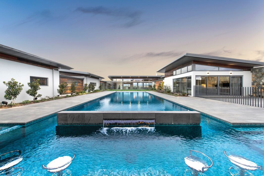 large pool with water feature on backyard of large home
