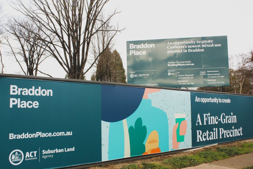 brightly coloured hoardings around a vacant block of land on Northbourne Avenue, Canberra that has just been sold to a developer