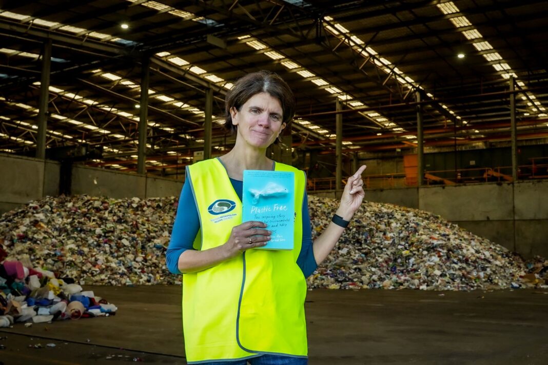 Rebecca Prince-Ruiz stands in front of waste at a materials recovery facility