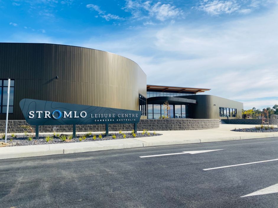 Artist's render of exterior of new indoor pool and recreation centre with big curved wall and glass entry way