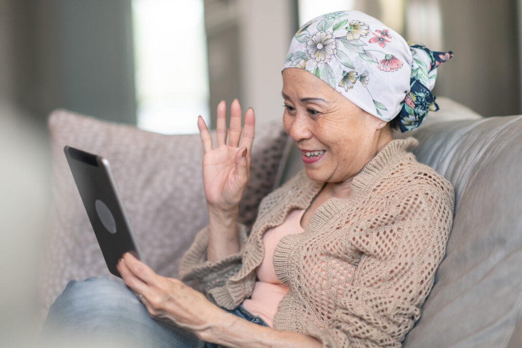 Woman with cancer video chats with friends on digital tablet