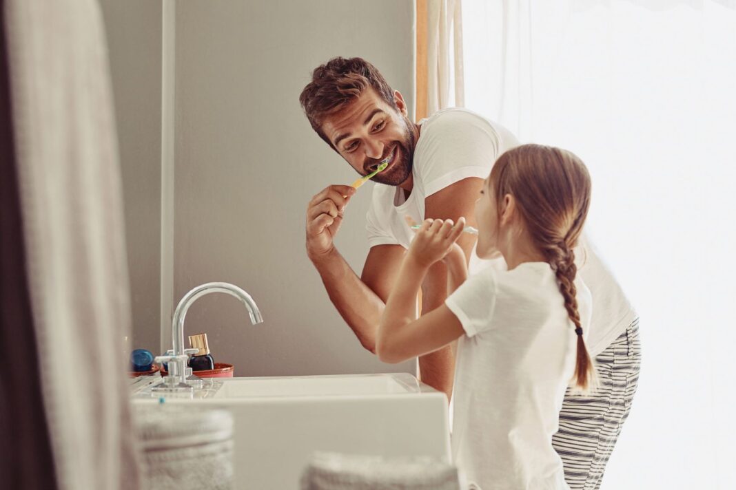 dad and daughter brushing teeth together