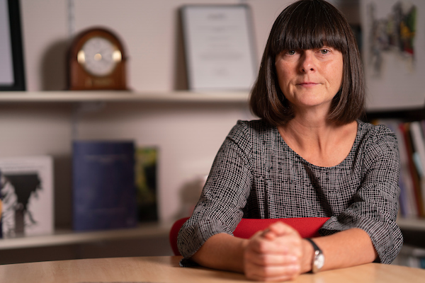 Female academic with dark hair sitting at a desk