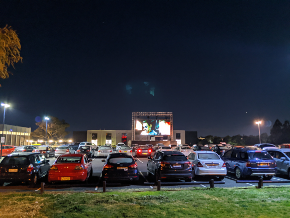 many cars lined up watching a movie at a drive-in