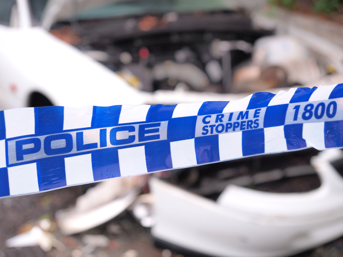 Police tape cordoning off a area with a damaged car