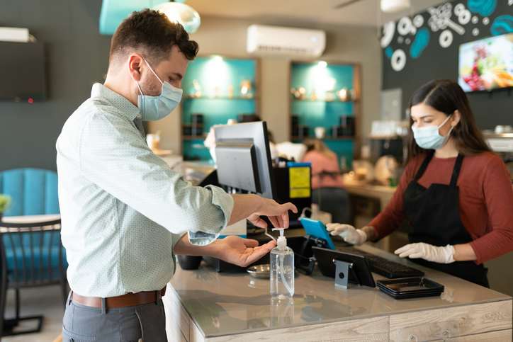 A customer applies hand sanitiser at a cafe
