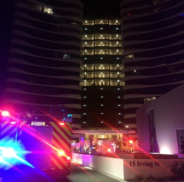 fire truck with lights glowing in the dark outside hi-rise apartment block with lights glowing on several floors