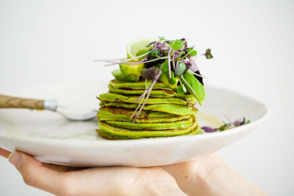Savoury matcha pancakes on a plate being held