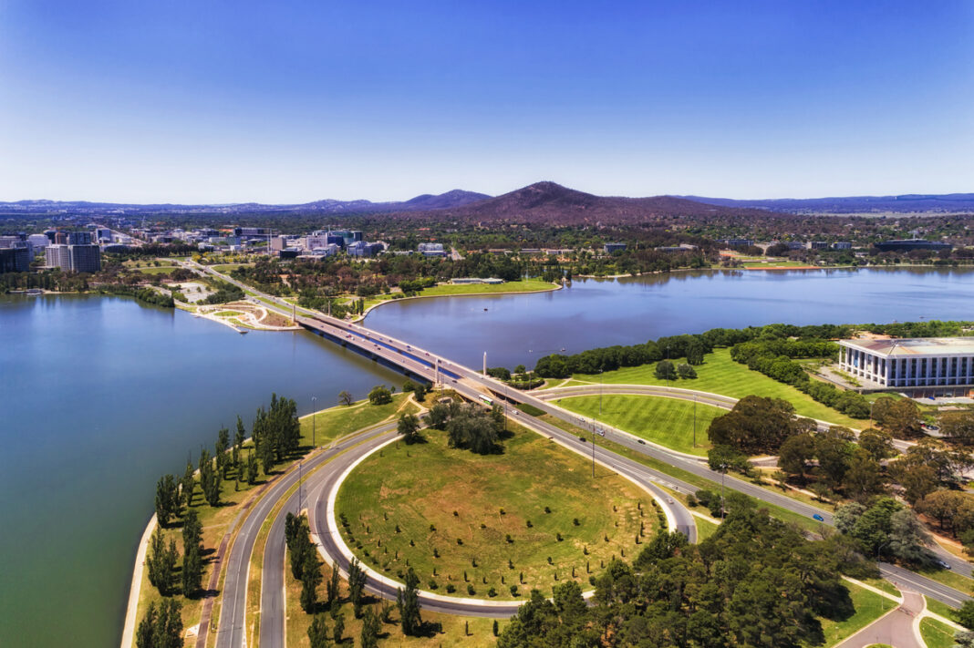 Commonwealth avenue and bridge over Burley Griffin lake in Canberra between city CBD and federal government capital hill triangle area with local streets, roads, parks and buildings.