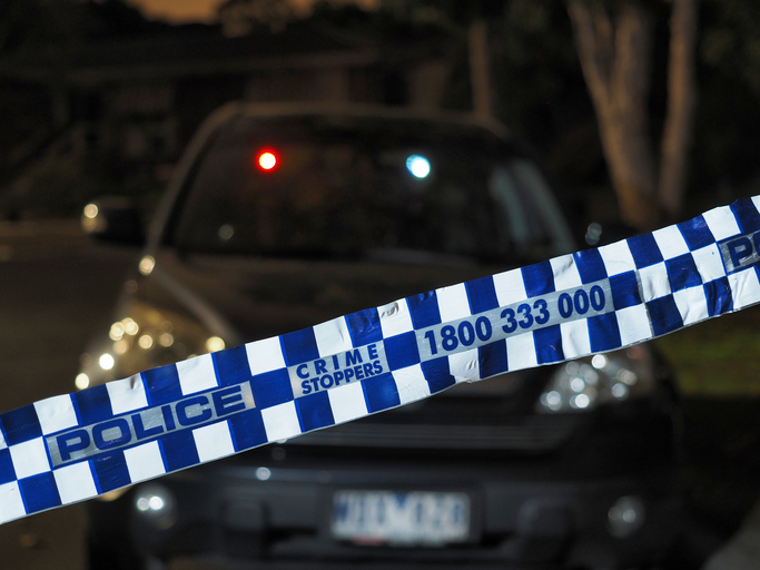 Police tape cordoning off a car after dark