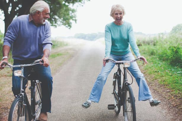 elderly couple riding bikes and smiling