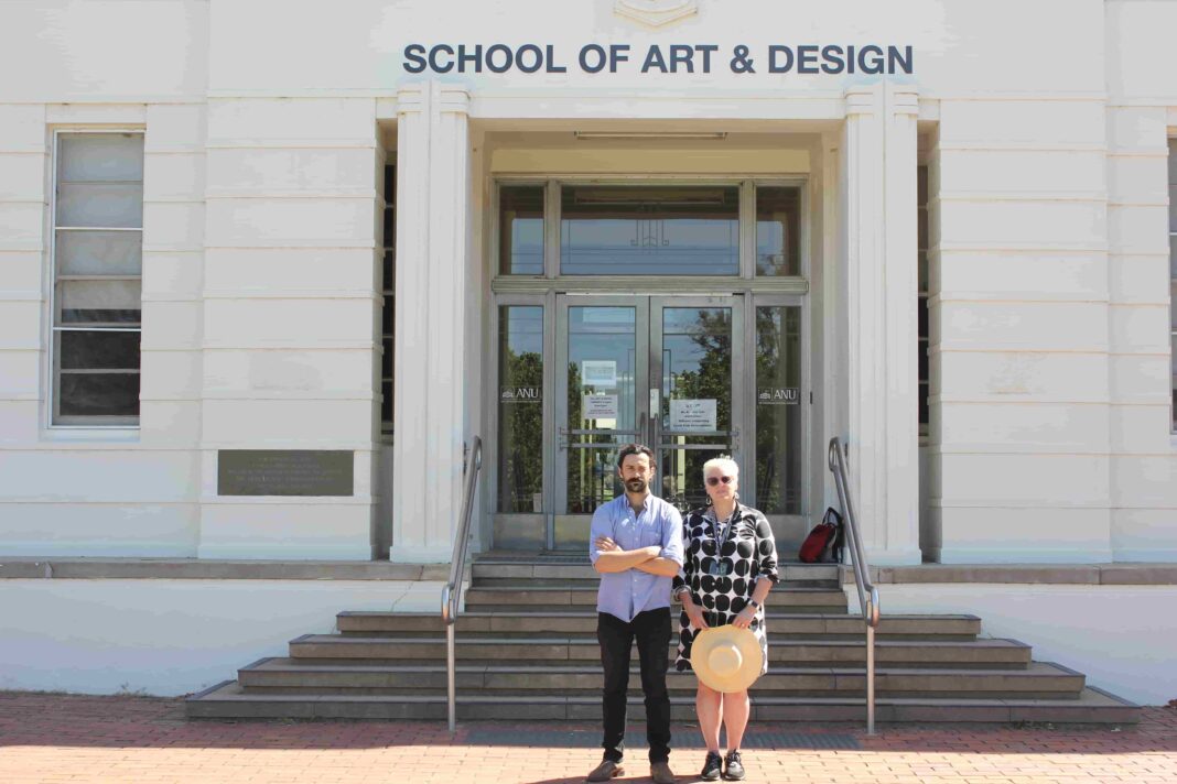 A man and woman standing outside the School of Arts & Design, an art deco building at the Australian National University