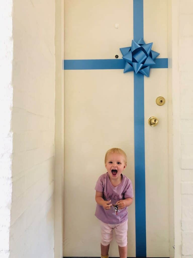 little girl smiling in front of a door