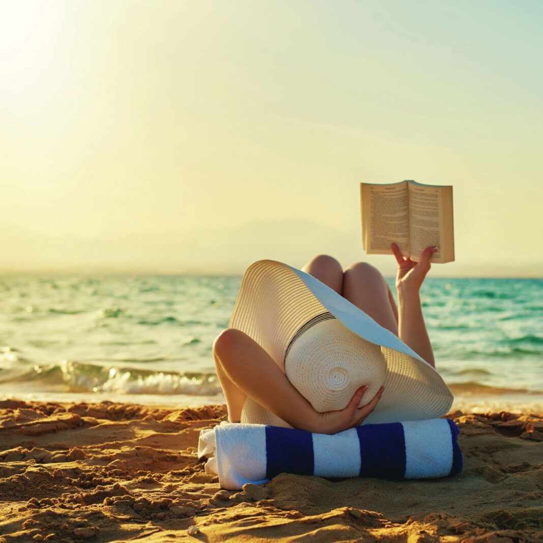 woman reading a book by the beach