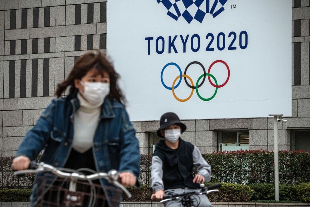 TOKYO, JAPAN - MARCH 13: People cycle past a banner for the Tokyo Olympics on March 13, 2020 in Tokyo, Japan. Excluding the Diamond Princess cruise ship cases, the number of coronavirus infections in Japan reached 684 today as United States President Donald Trump suggested the Tokyo Olympics should be postponed to next year. (Photo by Carl Court/Getty Images)