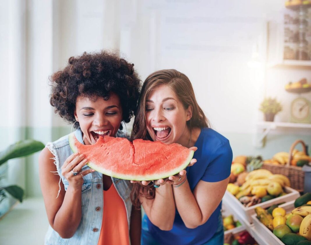 two women biting into a watermelon