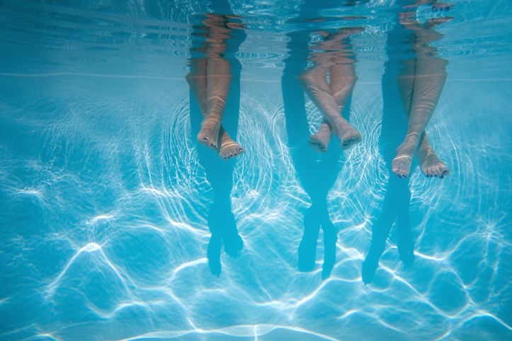 Keeping cool in a heatwave: three sets of legs underwater in a pool.