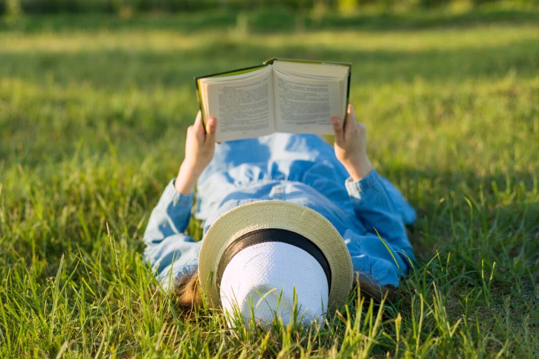 person laying on the grass reading