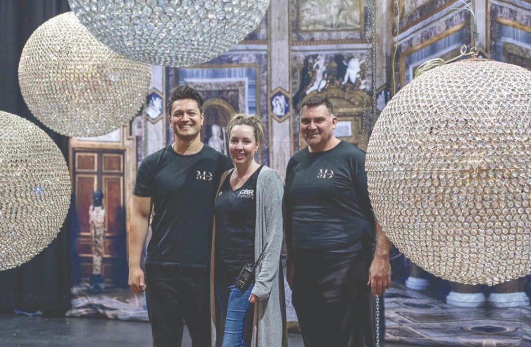 three people standing near chandeliers