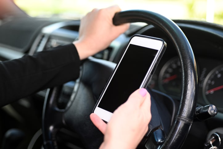 Woman using mobile phone while driving a vehicle.