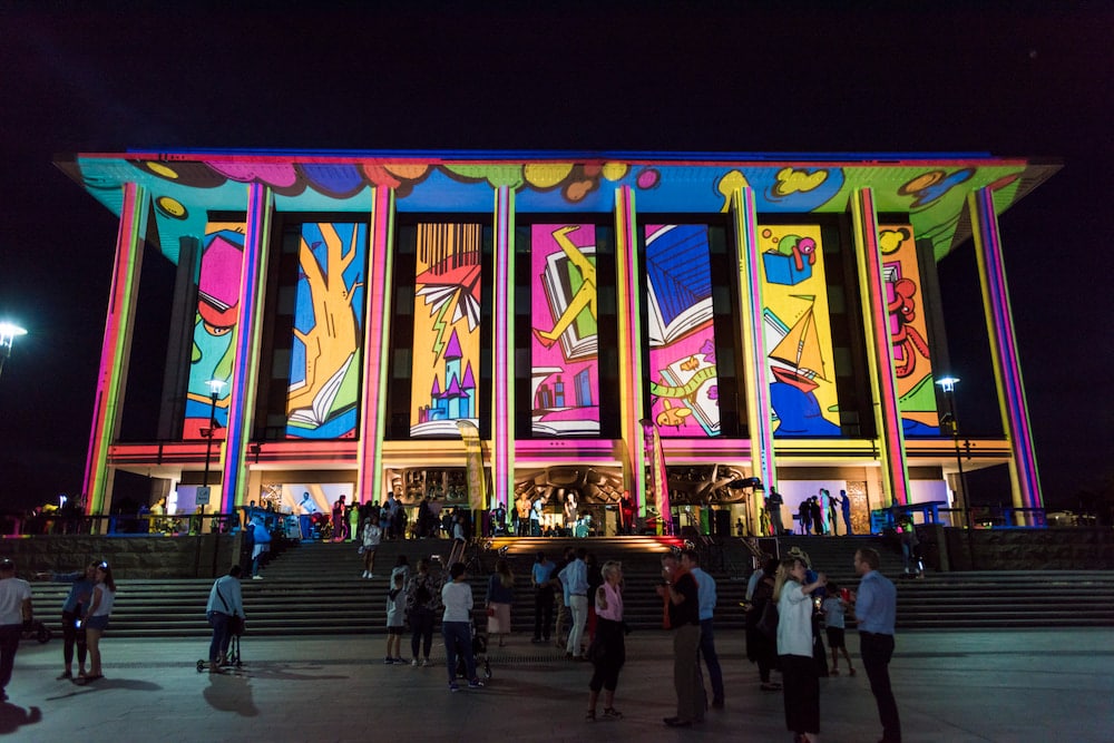 colourful illustrations illuminating the neo-Hellenic facade of the National Library of Australia at night