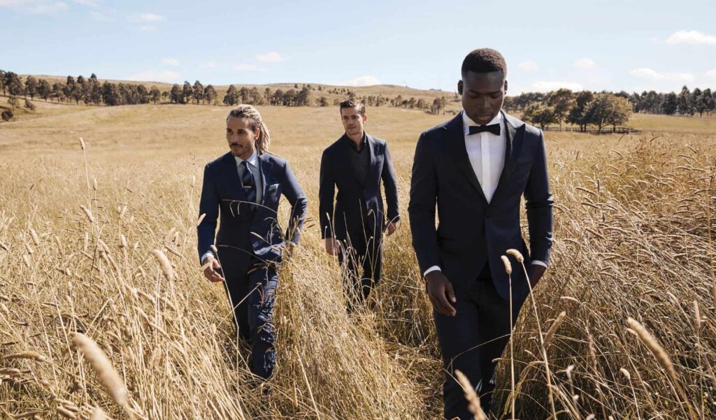three men in suits walking in a field