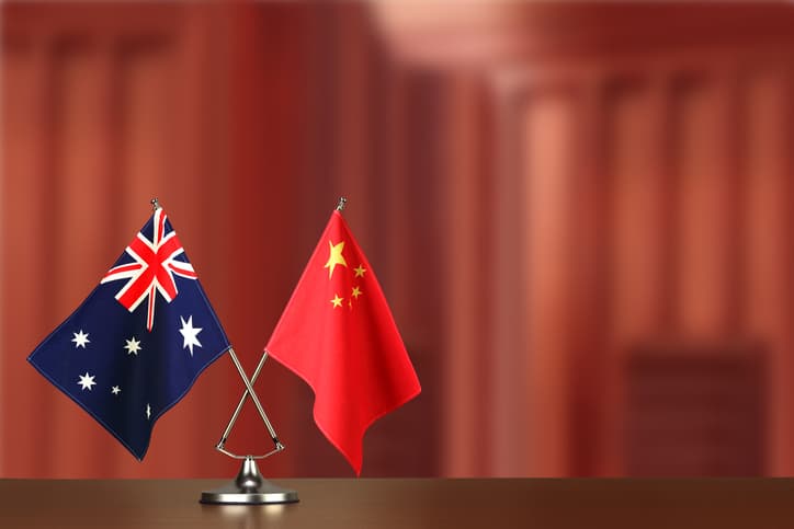 Two crossed national flags of Australia and China on wooden table