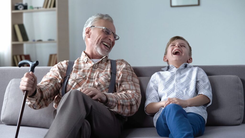 grandfather and grandson laughing on the couch