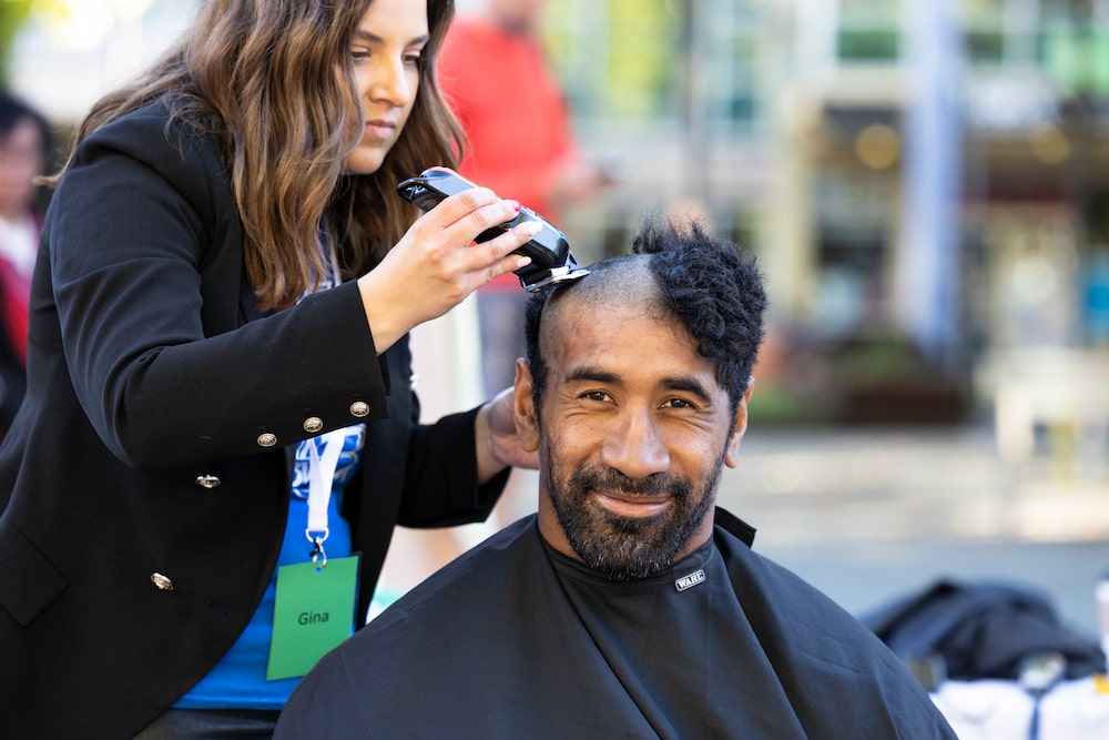 Canberra Raiders prop Sia Soliola smiles while his head is shaved