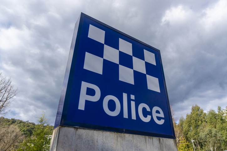 blue and white check police sign on concrete block with cloudy sky above