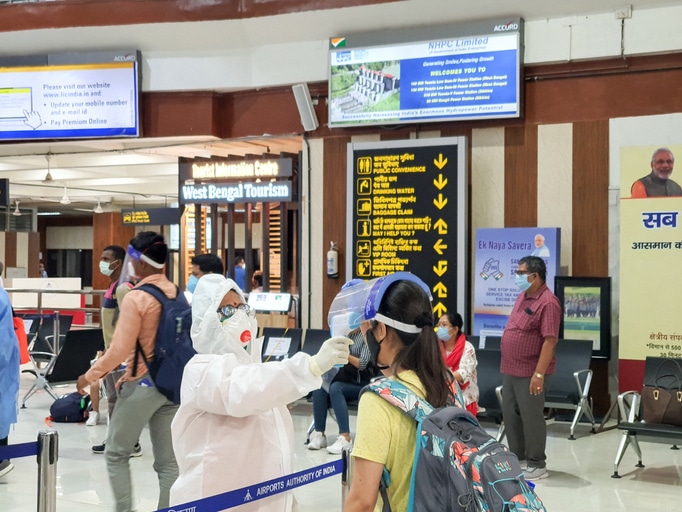 Passenger in Indian airport having temperature checked by person covered in Personal Protection Equipment