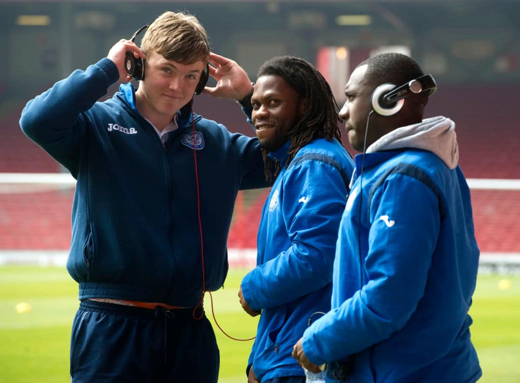 three young male footballers listening to music through headphones