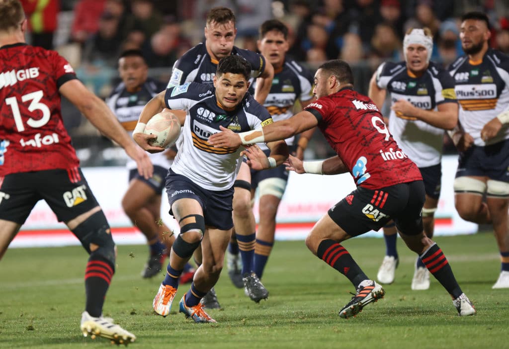 CHRISTCHURCH, NEW ZEALAND - MAY 15: Noah Lolesio of the Brumbies tries to evade the tackle of Bryn Hall of the Crusaders during the round one Super Rugby Trans-Tasman match between the Crusaders and the ACT Brumbies at Orangetheory Stadium on May 15, 2021 in Christchurch, New Zealand. (Photo by Peter Meecham/Getty Images)