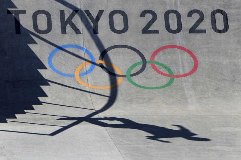 practising skateboarder casts shadow over Tokyo Olympic Games symbol on skateboarding park