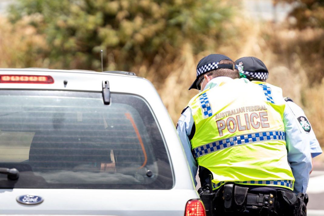Two police officers check a car entering the ACT from NSW