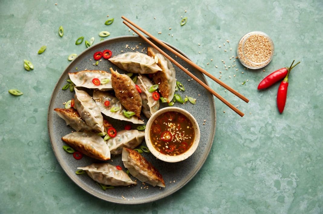 platter of gyoza dumplings with chopsticks and chili sauce