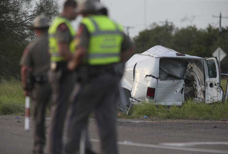 Texas Department of Public Safety officers stand near a vehicle where multiple people died after the van carrying migrants tipped over just south of the Brooks County community of Encino on Wednesday, Aug. 4, 2021, in Encino, Texas