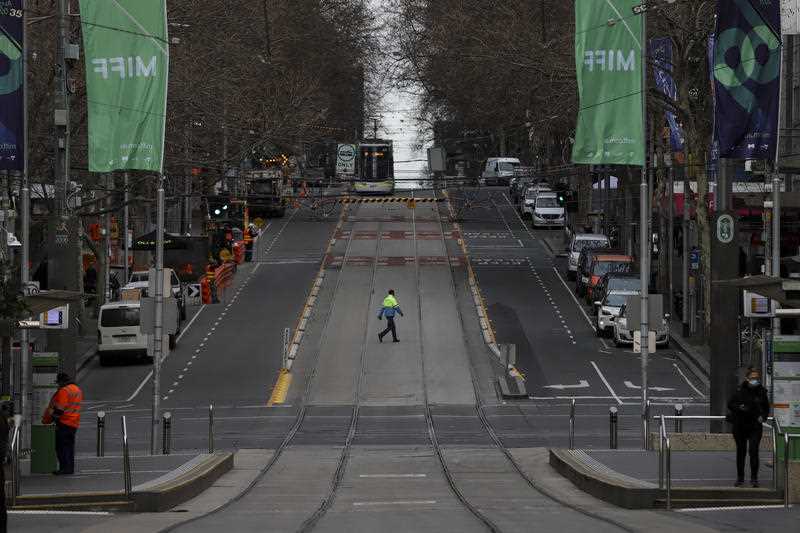 A worker is seen crossing a quiet Bourke Street in Melbourne, Friday, August 6, 2021.