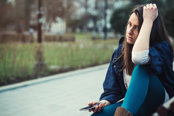 Sad woman holding her mobile phone