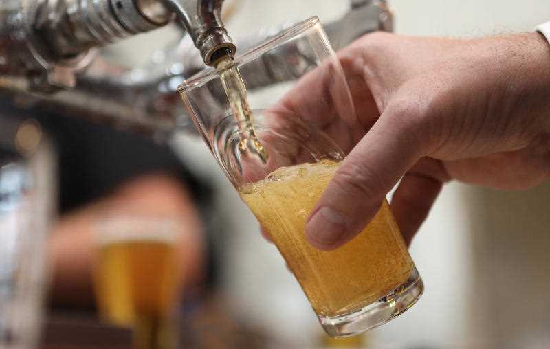 a glass of beer is seen being poured on tap at a pub