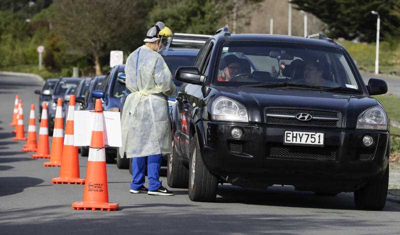 Medical staff prepare take a COVID-19 test from a visitor to a drive-through community based assessment centre in Christchurch, New Zealand