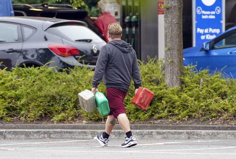 A man carries containers to a petrol station in Bracknell, England,