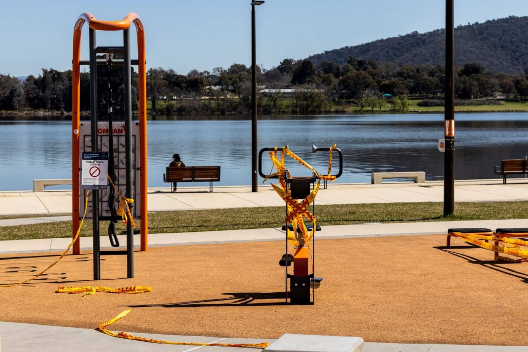 A Canberran sits alone by the lake at Henry Rolland Park where the public exercise equipment has been cordoned off. Photo: Kerrie Brewer