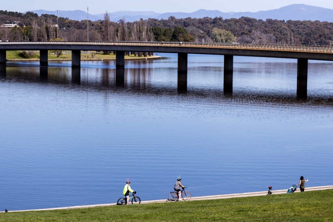 a few socially distanced people walking or cycling around Lake Burley Griffin in Canberra on a sunny spring day
