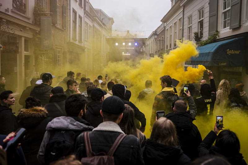 Activists wade through yellow-coloured smoke as they rally during a music demonstration against the coronavirus pandemic measures, in the center of Breda, The Netherlands, 20 November 2021